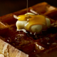 Close-up of waffle covered with syrup and pat of butter